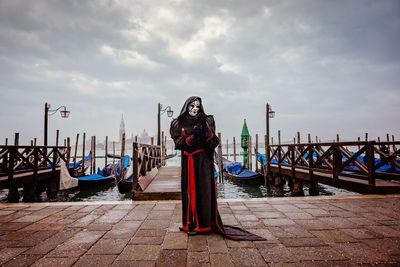 Man standing on pier at canal