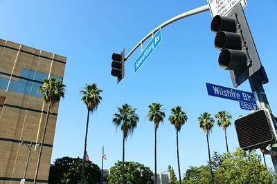 Low angle view of road and trees against clear blue sky