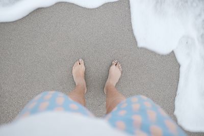 Low section of man standing on sand