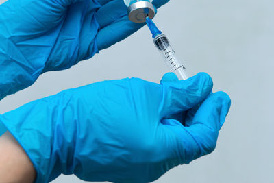 Cropped hands of doctor holding syringe with vial at hospital