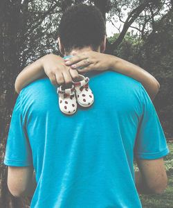 Woman hugging man while holding baby booties at forest