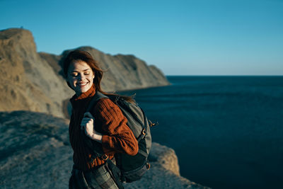 Young woman standing by sea against sky