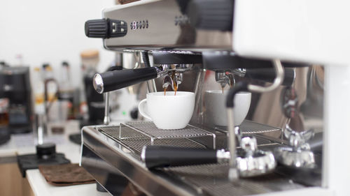 Barista makes artistic latte with espresso machine in cafe. 