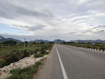 Empty road along landscape against sky