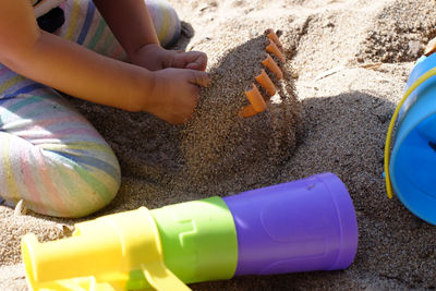 Midsection of girl playing in sand at beach