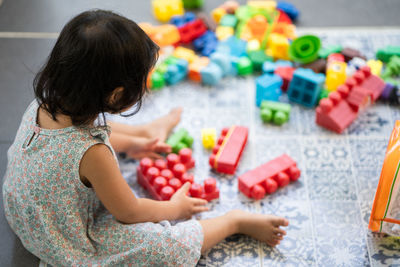 Cute little girl playing plastic building block outdoor.