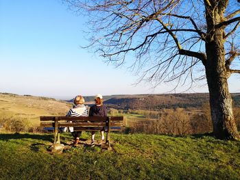 People sitting on bench against clear sky