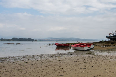 Boat moored on beach against sky