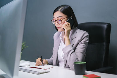 Young woman using mobile phone while sitting on table