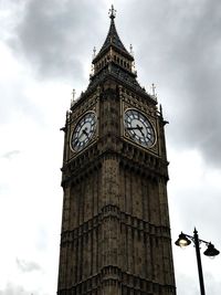 Low angle view of clock tower against cloudy sky