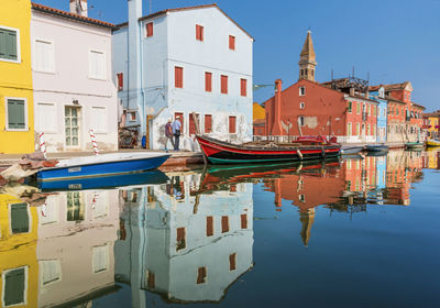 Boats moored in canal by buildings in city