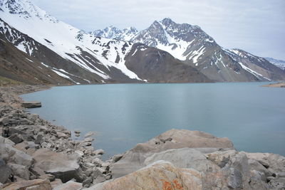 Scenic view of lake by snowcapped mountains against sky