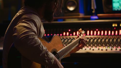 Midsection of man playing guitar