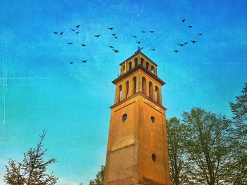 Low angle view of birds flying against blue sky
