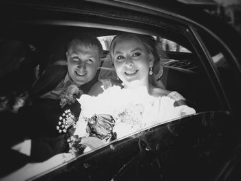 Portrait of happy newlywed couple sitting in car