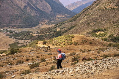 Senior woman hiking down the mountain slope in peru
