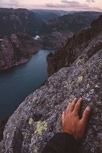 Hand on rock at norwegian fjords view on the background.