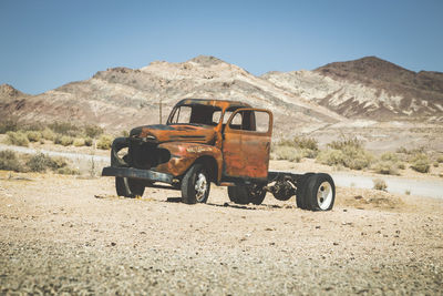 Abandoned truck on land in desert against clear sky
