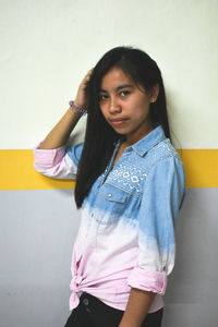 Portrait of woman standing against wall