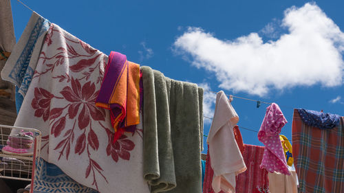 Laundries drying on rope against blue sky