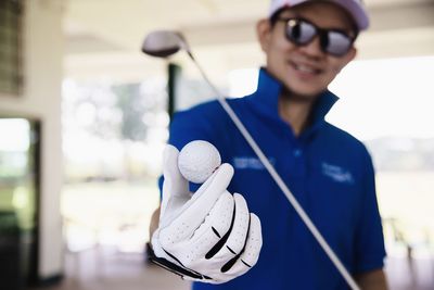 Smiling man holding golf club and ball