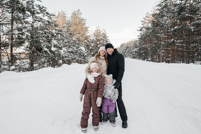 Dad and mom and two daughters walk through the snowy forest. high quality photo