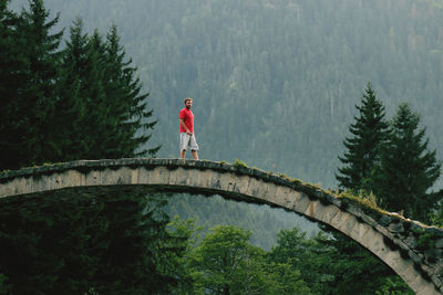 Man standing by bridge in forest