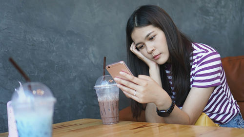 Young woman looking away while sitting on table