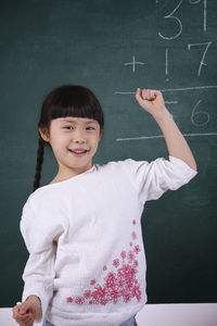 Girl smiling while learning mathematics on blackboard