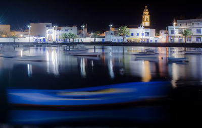 River by illuminated buildings in city at night