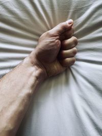 Close-up of man hand on bed
