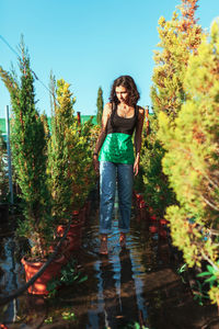 Full length portrait of woman standing against plants