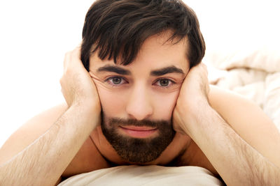 Portrait of young man on bed against white background