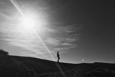 Silhouette man walking on landscape against sky