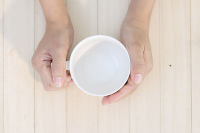 Directly above shot of hand holding tea cup on table