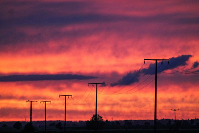 Silhouette electricity pylon against sky during sunset