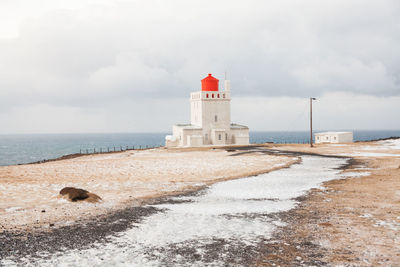 Lighthouse on beach against sky