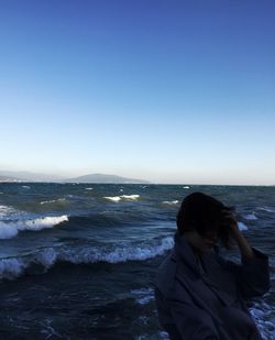 Woman standing on beach against clear sky