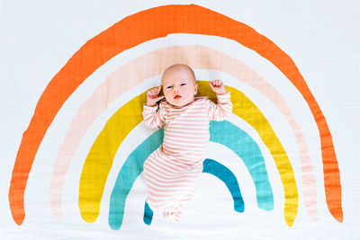 A newborn baby girl lying on a rainbow painted blanket