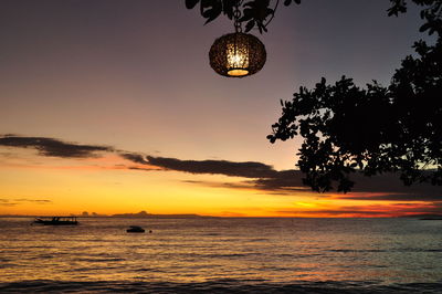 Silhouette tree by sea against sky during sunset