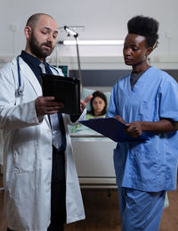 Male and female doctors examining reports at hospital