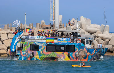 People on boats in sea against clear sky