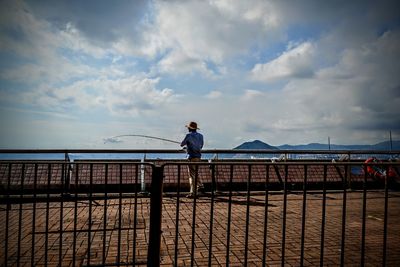 Man sitting on railing against sea