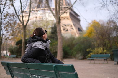 Side view of man sitting on bench in park