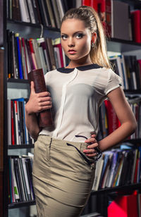 Woman holding book while standing at library