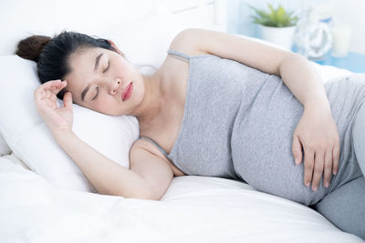 Pregnant woman sleeping on bed