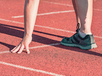 Bent woman on the athletics track exercises in the position of the start