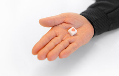 Cropped hand of woman with pills against white background