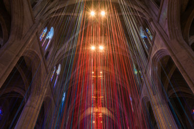 Low angle view of illuminated lights hanging on ceiling of building