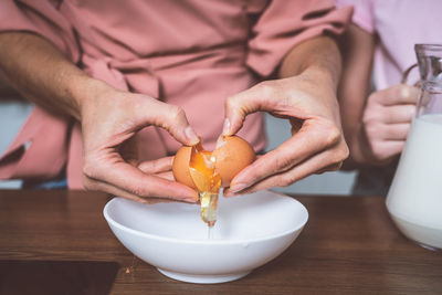 Midsection of woman pouring egg in bowl